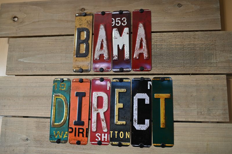 Vintage Alabama license plates arranged on weathered wood spelling Bama Direct