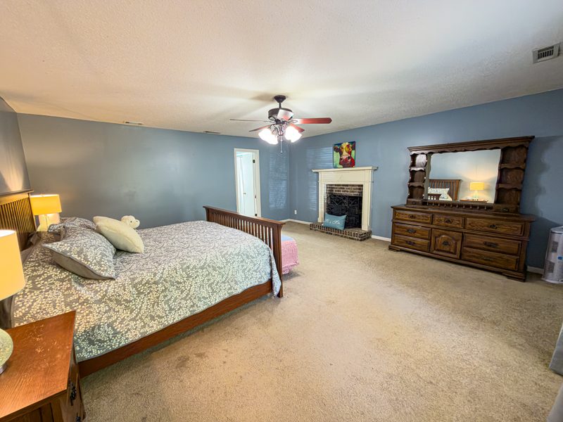 Bedroom with a fireplace, a wood dresser and windows on two walls