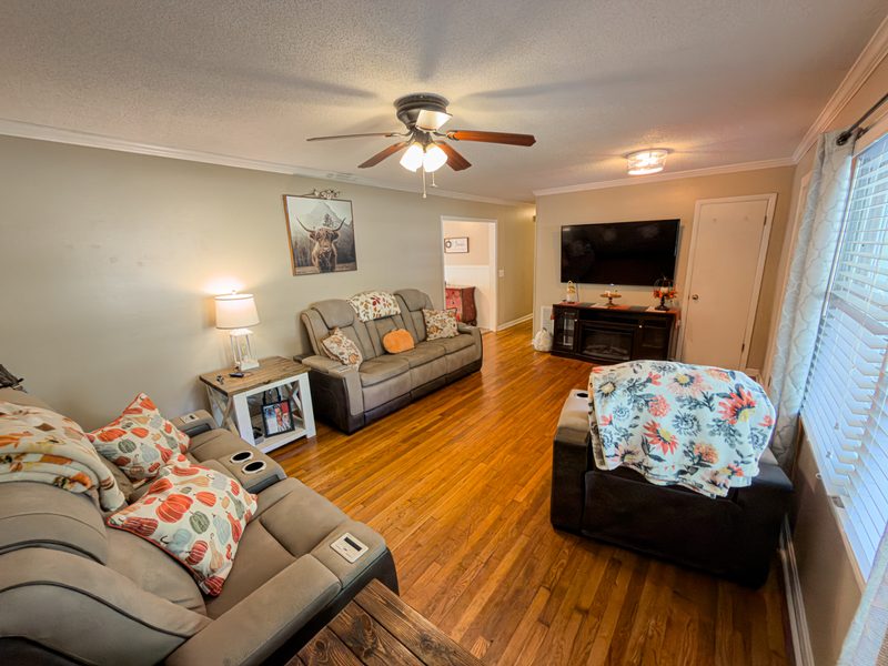 Living room with hardwood floors, a sectional and a wall mounted television